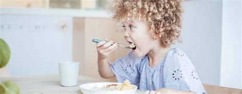 Illustratie van een kind dat zelfstandig eet van een kleurrijk bord