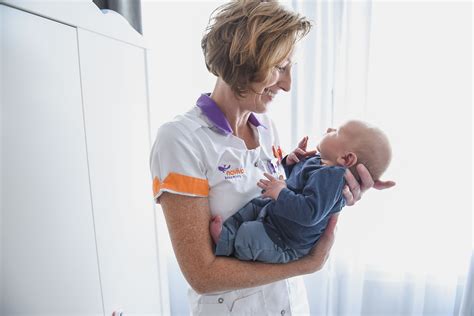 Foto van een kraamverzorgende die liefdevol voor een baby zorgt