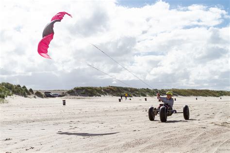 Illustratie van een kitebuggy op het strand met een vlieger in de lucht