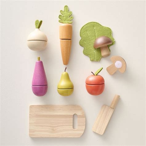 Een gedetailleerde foto van een houten speelgoedkeukenset, inclusief fruit, groenten, snijplank en mes.