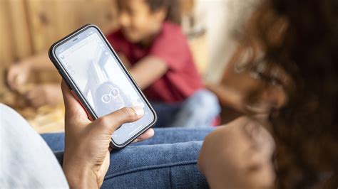 Illustratie van een kind dat nieuwsgierig naar een oude telefoon kijkt, met ouders op de achtergrond.