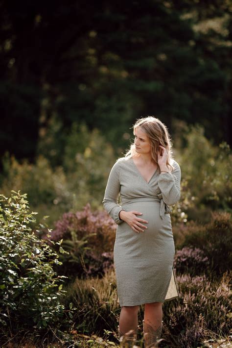 Een stel geniet van een zwangerschapsshoot in de natuur met een grote, ronde buik.