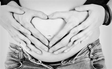 Gedetailleerde foto van handen die liefdevol de zwangere buik omvatten.