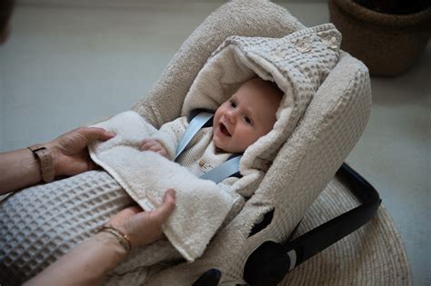 Illustratie van een baby die comfortabel slaapt in een autostoel met een Koeka deken