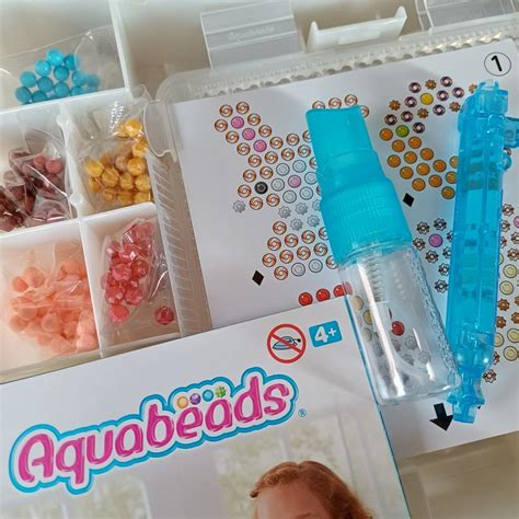 Een kind dat Aquabeads op kunstnagels aanbrengt
