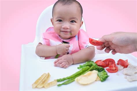 Baby die met de handen eet, fingerfood op de tafel.