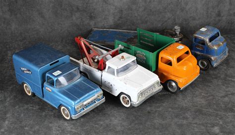 Een verzameling van diverse vintage Tonka vrachtwagens en bouwmachines, waaronder kiepwagens, graafmachines en brandweerwagens.