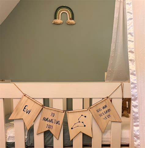 Foto van een babykamer met een houten geboorteslinger boven het ledikant.