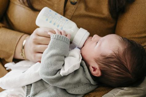 Illustratie van een baby die een fles met moedermelk drinkt, met op de achtergrond een aantal opgestapelde moedermelk bewaarzakjes.