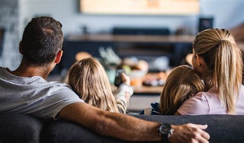 Een gezin dat thuis gezellig in onesies op de bank zit