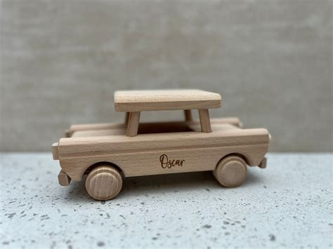 Close-up van een kinderhand die een houten speelgoedauto duwt, met focus op de motorische ontwikkeling.