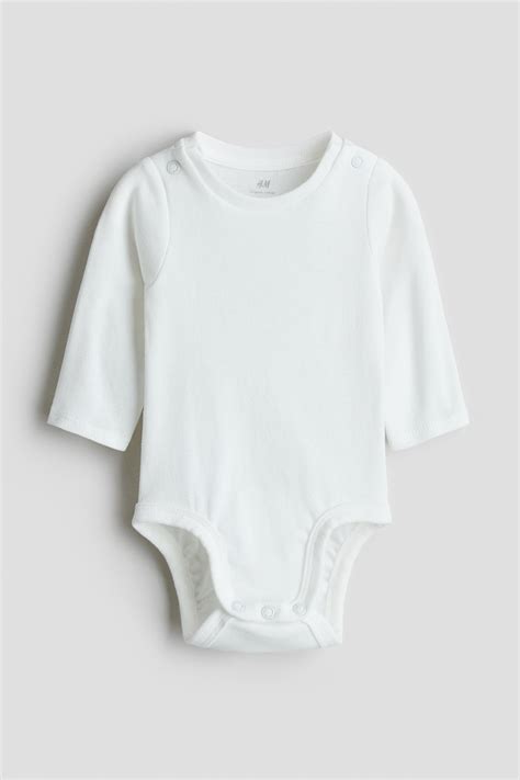 Close-up van zachte, biologische katoenen babykleding met drukknopen voor eenvoudig aan- en uitkleden.