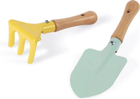 Een kind dat met een houten schepje en harkje in de tuin speelt.