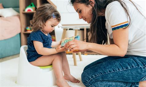Baby die op een potje zit, met een ouder die toekijkt.