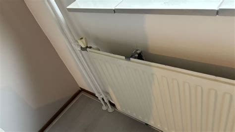 Een illustratie die toont hoe twee personen een radiator veilig van de muur tillen.