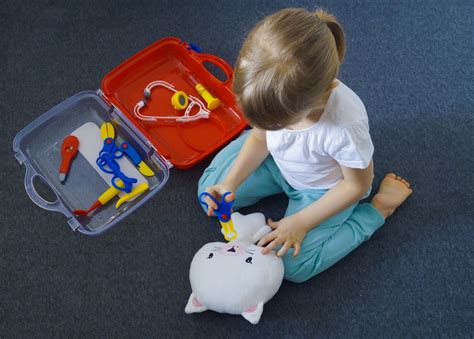 Een kind speelt doktertje met een knuffelbeer en een speelgoedstethoscoop.