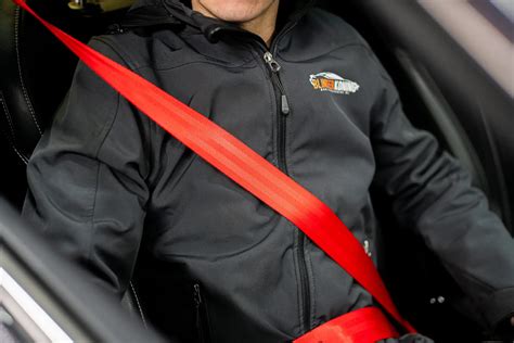 Illustratie die de correcte routing van de autogordel door de gekleurde punten op een autostoeltje toont