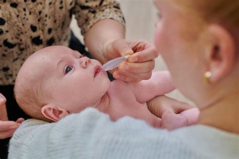 Illustratie van een baby die het rotavirusvaccin via druppels in de mond krijgt.