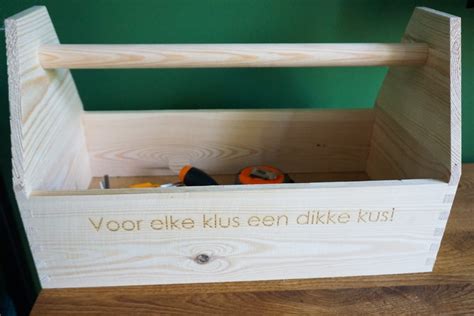 Houten gereedschapskist met diverse accessoires, waaronder een boormachine en tandwielen.