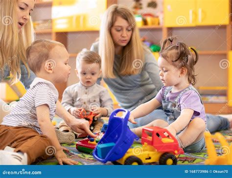 Een sfeervolle foto van jonge kinderen die spelen onder toezicht van hun ouders in een gemeenschapsruimte.