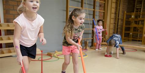 Een dynamische foto van kleuters die deelnemen aan een bewegingsles met een trainer.