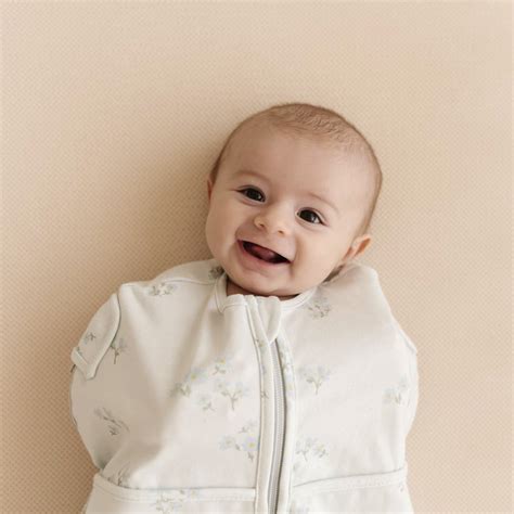 Baby die in een Puckababy slaapzak ligt met armen binnenin.
