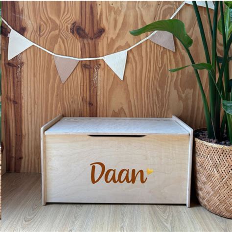 Een kinderkamer met een witte houten speelgoedkist met naturelkleurige houten pootjes in Scandinavische stijl.