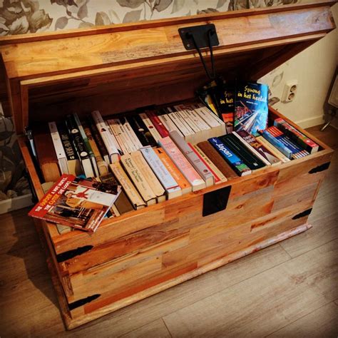 Een houten boekenkist op kinderhoogte, gevuld met kleurrijke kinderboeken.