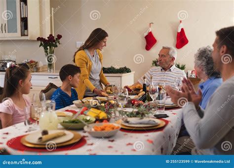 Foto van een grote familie die samen aan een lange eettafel zit.