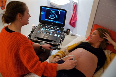 Verschillende echo-apparaten en een zwangere vrouw die naar de echo kijkt