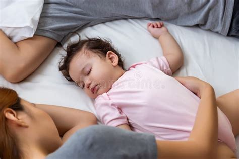 een vader die de baby voedt terwijl de moeder slaapt