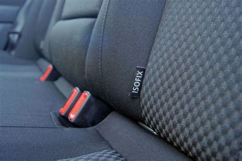 Illustratie van een correcte installatie van een autostoeltje met Isofix en autogordel, met aandacht voor de plaatsing van de gordel.