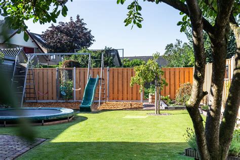 Foto van een kindvriendelijke tuin met speeltoestellen en dierenverblijf.