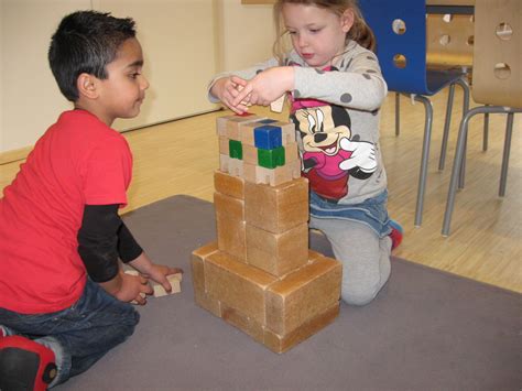 Een peuter die met plezier aan het bouwen is met Duplo blokken.