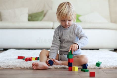 Foto van een peuter die enthousiast speelt met grote foam bouwblokken.
