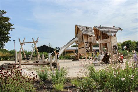Een kleurrijke strandtent aan een meer met een speeltuin op de achtergrond.