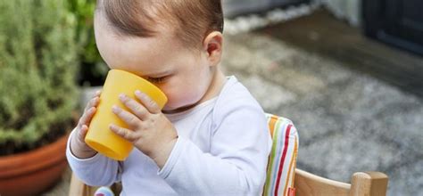 Afbeelding van een peuter die lachend uit een beker drinkt