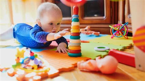 Een baby die probeert te grijpen naar een speeltje, illustreert de ontwikkeling van de fijne motoriek.