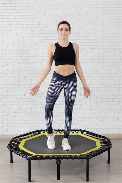 Vrouw die voorzichtig op een trampoline springt, met een glimlach
