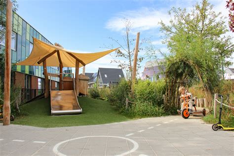 Buitenruimte van een kinderopvang met speeltoestellen en groen