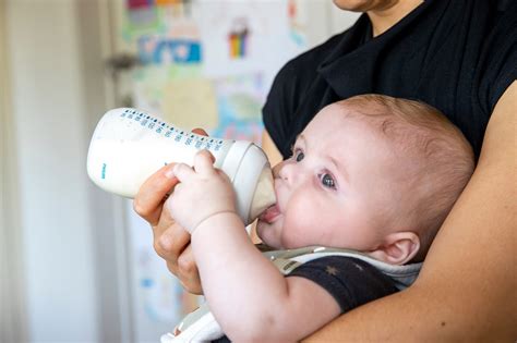 Baby drinkt uit een flesje gegeven door een ouder