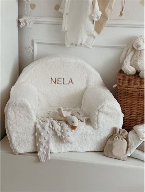 Een schattige teddy kinderstoel met een geborduurde naam erop, in een lichte, neutrale kinderkamer.