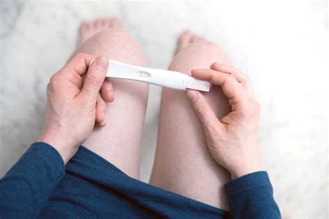 Vrouw die een zwangerschapstest vasthoudt met een mengeling van hoop en angst