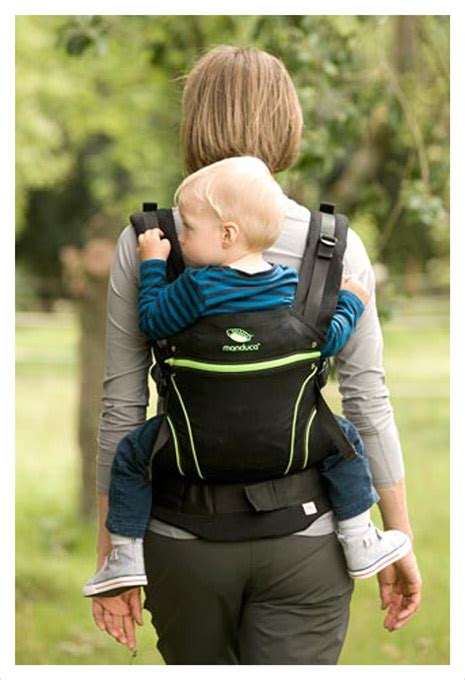 Een ouder die een peuter in een draagzak op de rug draagt, genietend van een wandeling in de natuur.