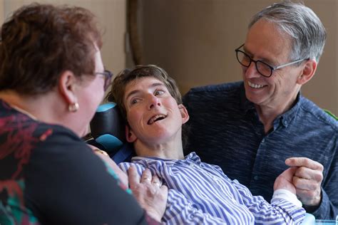 Een ouder die een peuter met een fysieke beperking draagt in een speciaal aangepaste draagzak.