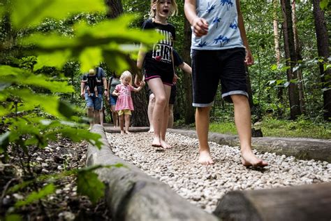 Kinderen die met plezier over een blotevoetenpad lopen, met verschillende texturen onder hun voeten.