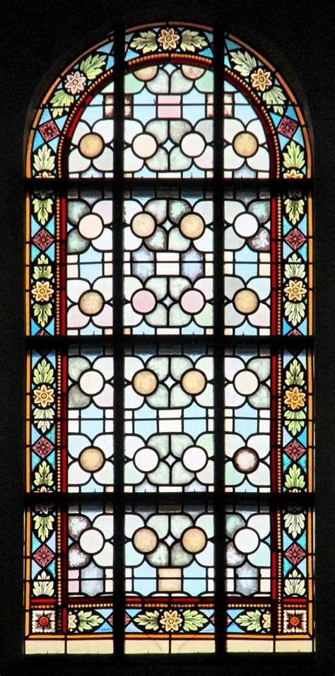 Gedetailleerd gebrandschilderd raam uit de Sint-Janskerk, met focus op de figuren en symboliek.