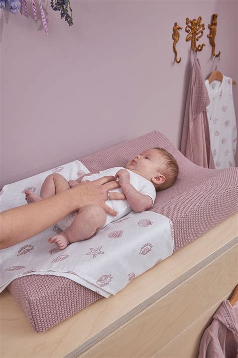 Een baby die comfortabel is ingebakerd in een Meyco hydrofiele swaddle XL met hartjesdessin.