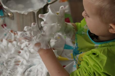 Een kind dat met scheerschuim en voedingskleurstof in bad schildert