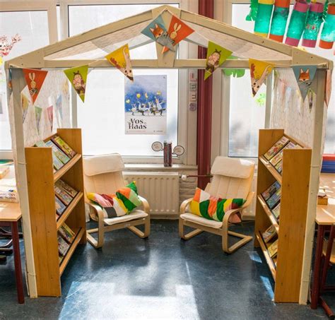 Een sfeervolle leeshoek naast een babybedje met een wandplank en een opvouwbare matras.